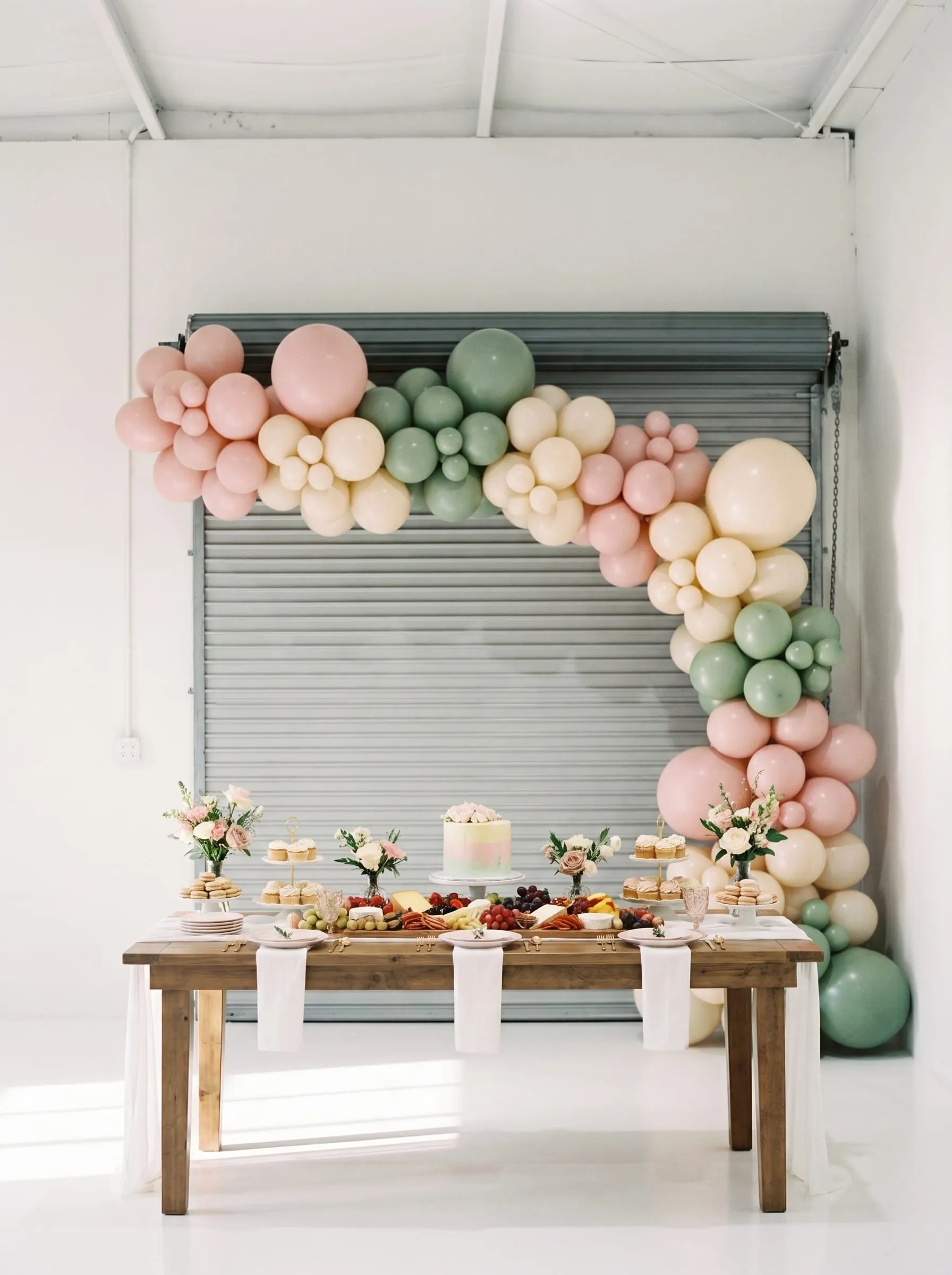 Pastel balloon arch and a dessert table styled for a baby shower