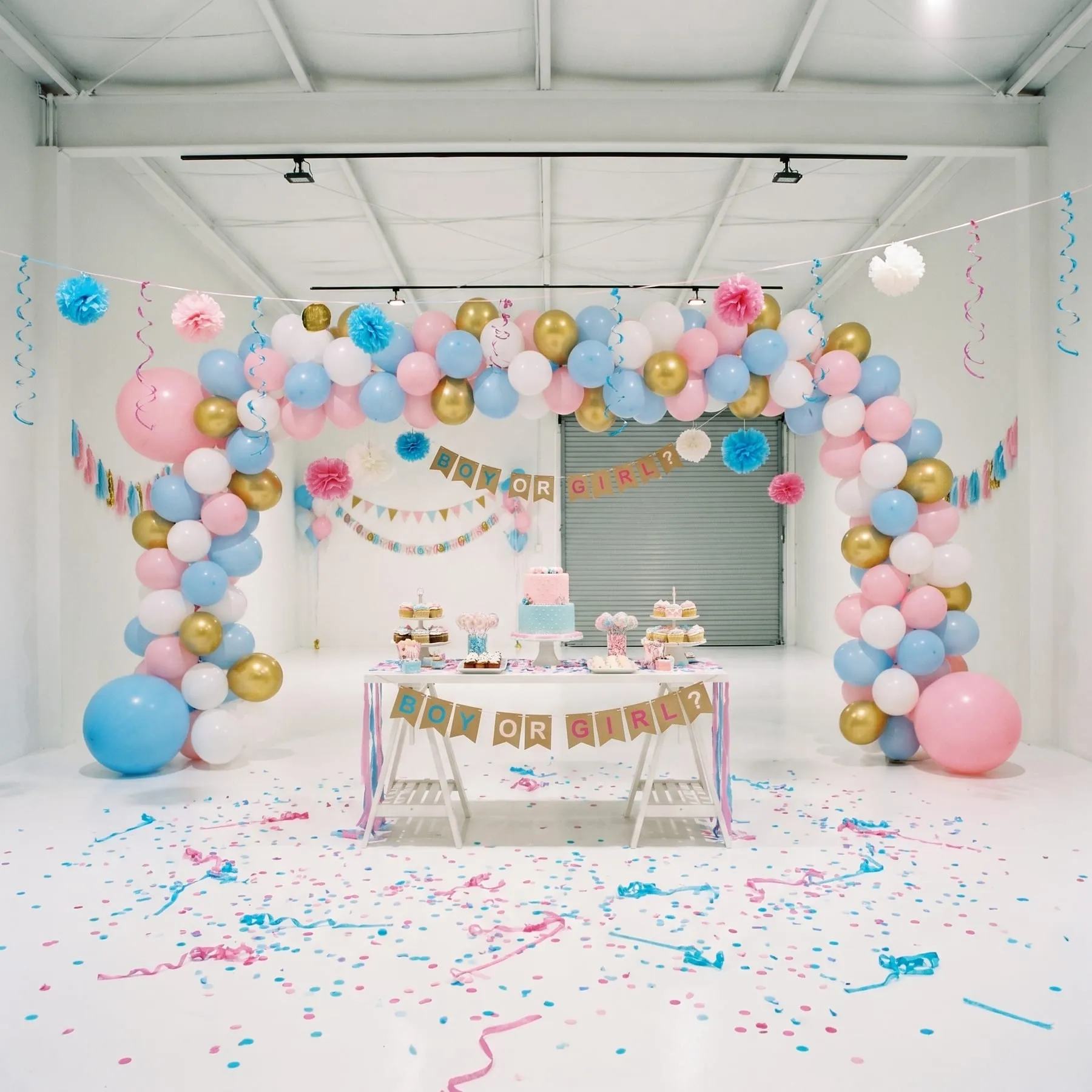 Pink and blue balloons and a cake table set up for a gender reveal