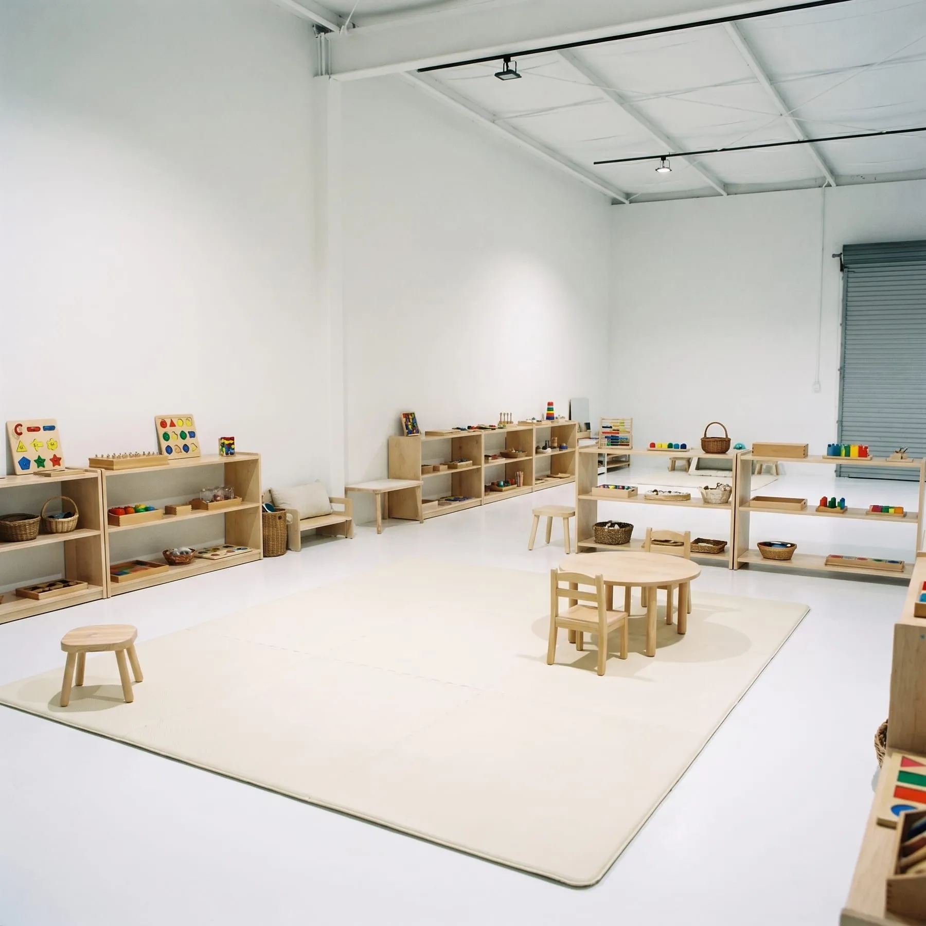A Montessori toddler classroom setup with wooden shelves and small chairs